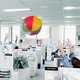 Workers throw a beachball in an office.