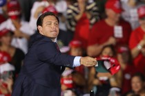 Ron DeSantis tosses hats to the crowd before the arrival of Donald Trump for his campaign event at Miami-Opa Locka Executive Airport in November 2020.