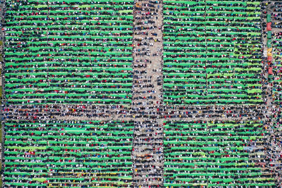 An aerial view of hundreds of people praying together.