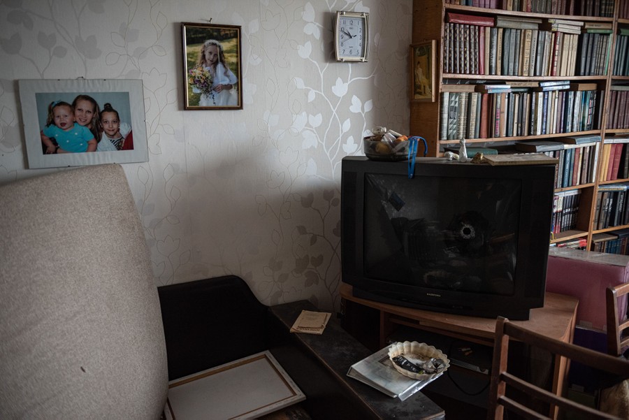 A view of a living room where a television set is seen with a bullet hole in its screen.