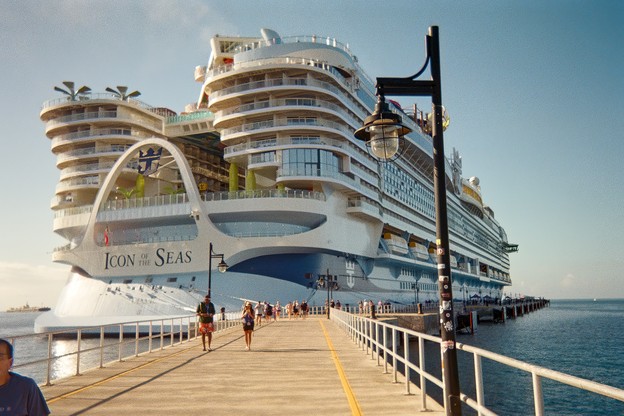 photo of Icon of the Seas, taken on a long railed path approaching the stern of the ship, with people walking along dock