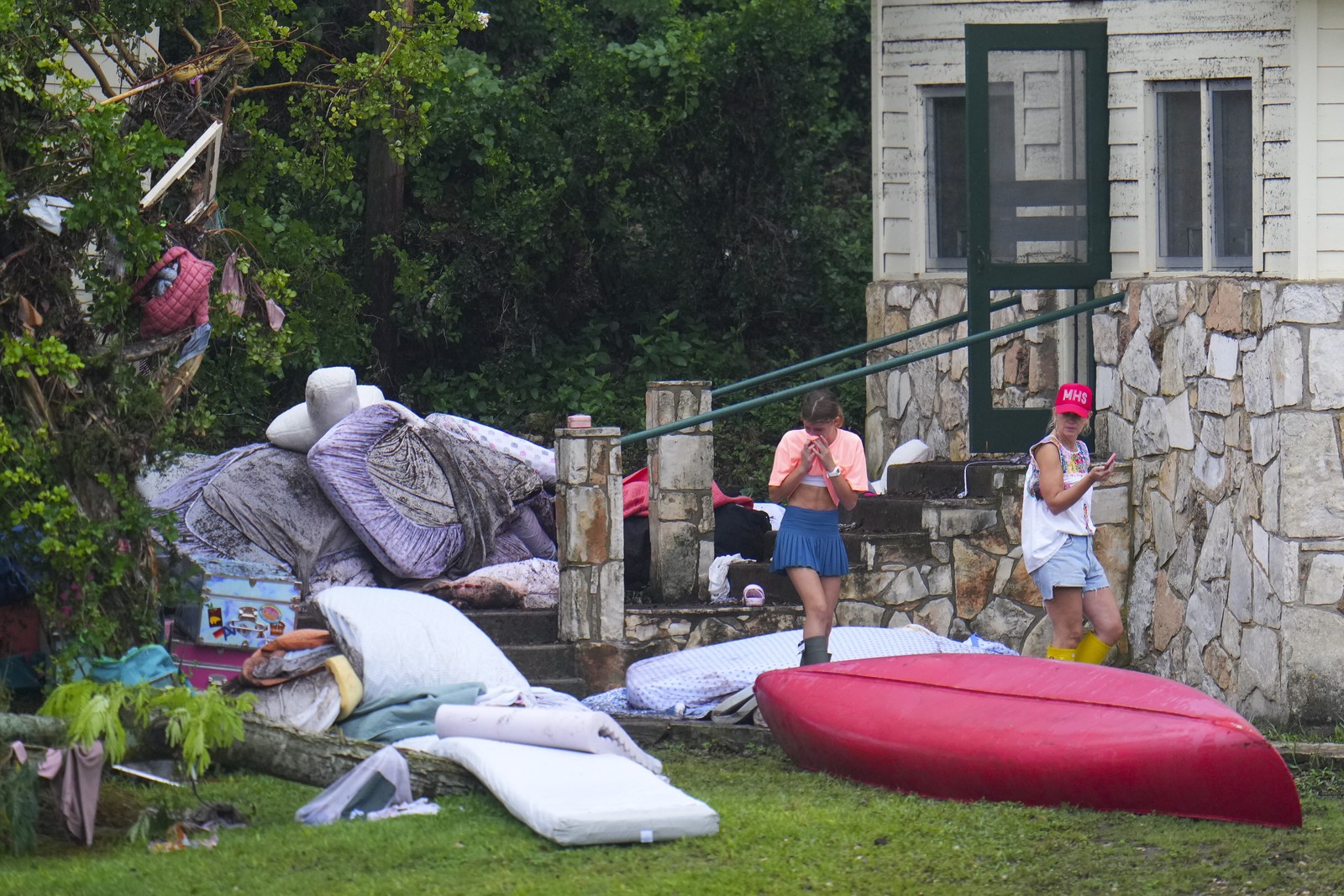 A person reacts while looking at bedding and other scattered belongings outside a camp building.