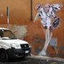 A nun takes a picture of a drawing of Pope Francis depicting him as a superhero on a wall near the Vatican.