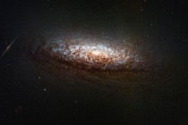 A telescopic view of a distant spiral galaxy dominated by thick lanes of dark dust