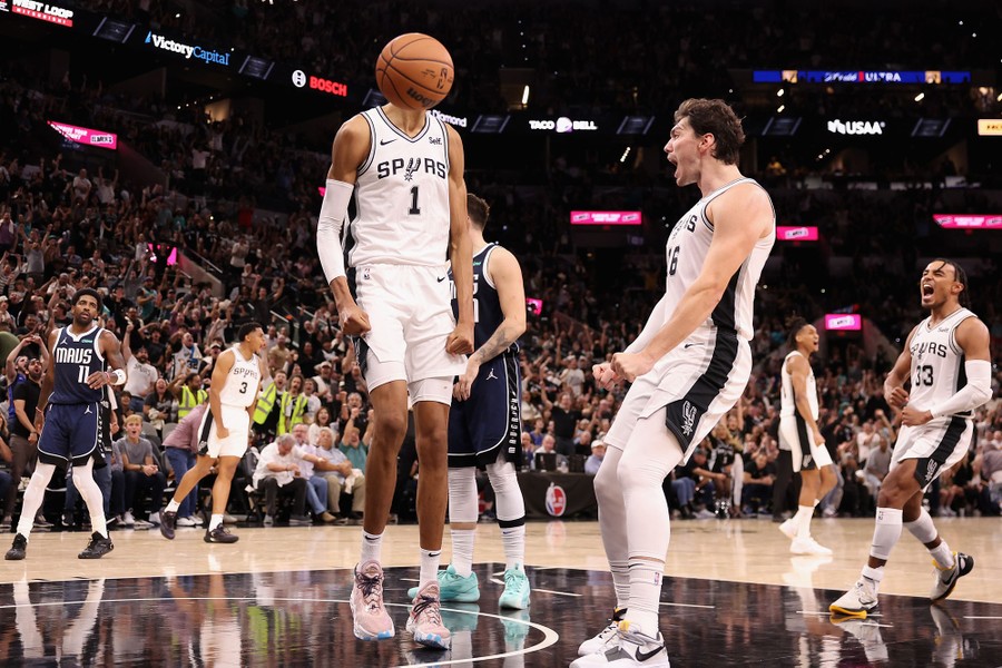 Basketball players celebrate after scoring. The bouncing ball appears at head-height, obscuring the face of one of the players.