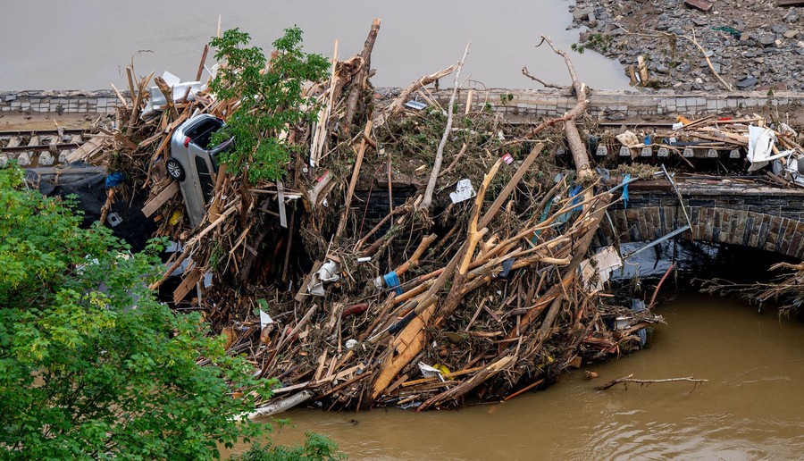 A pile of debris sits jammed up against a railroad bridge.