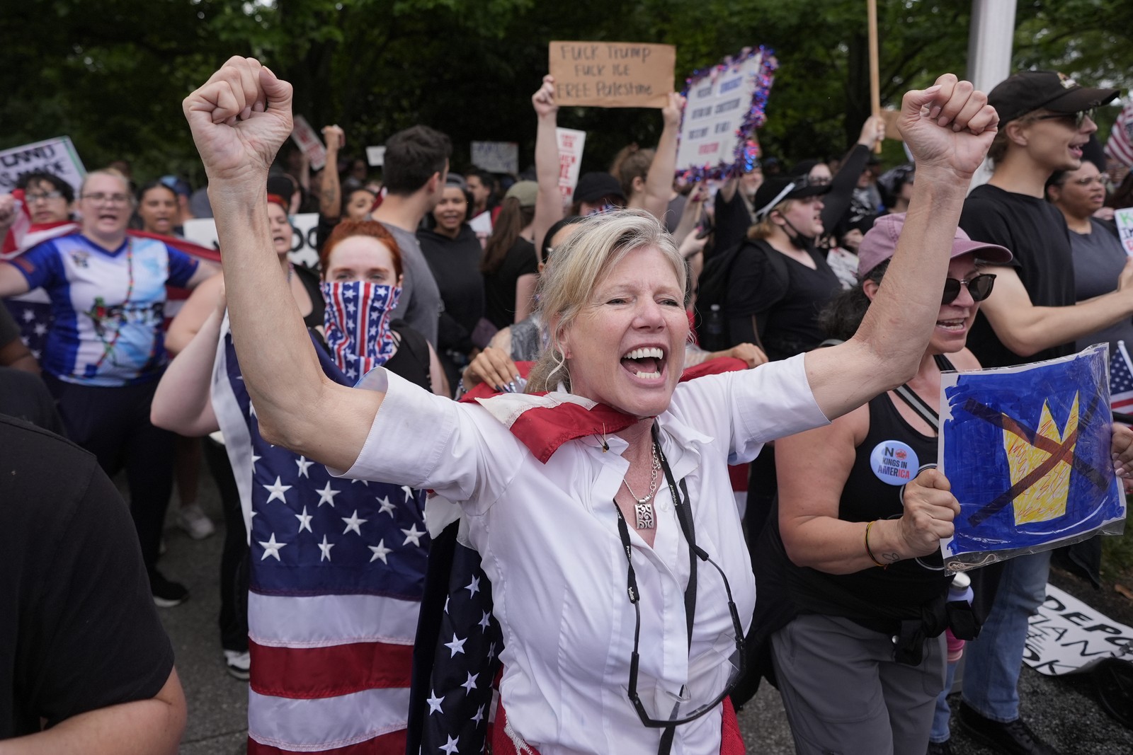 A woman yells during a protest, standing among others in a crowd.