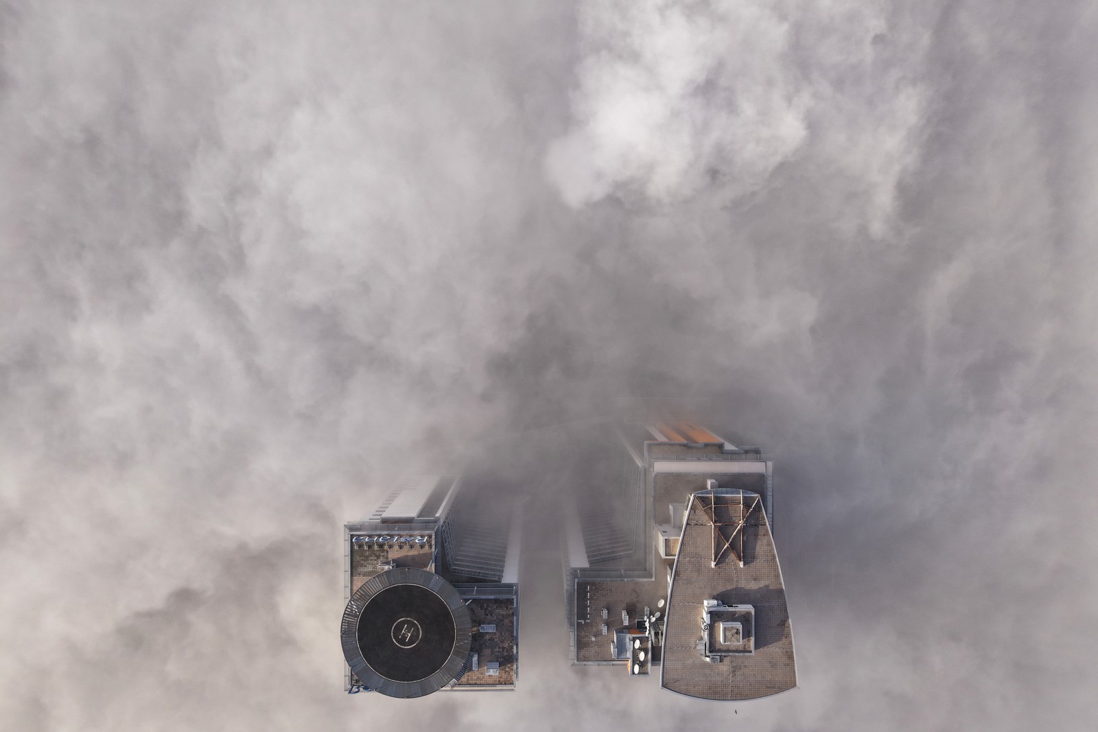 An aerial view of two tall buildings peeking through a dense layer of fog