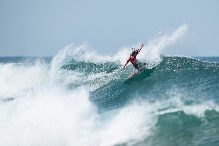 A surfer makes a turn atop a wave.