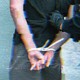 Blurry image of a man with his hands ziptied behind his back