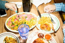 An overhead picture of two people sharing several dishes at a restaurant table