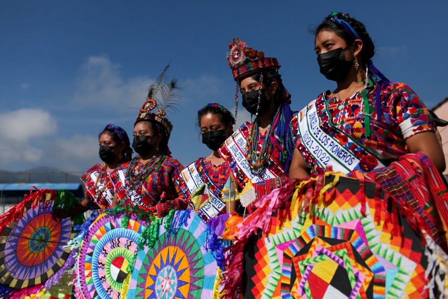 Women in colorful costumes pose for a photo during a festival.