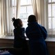 Two children look out a window