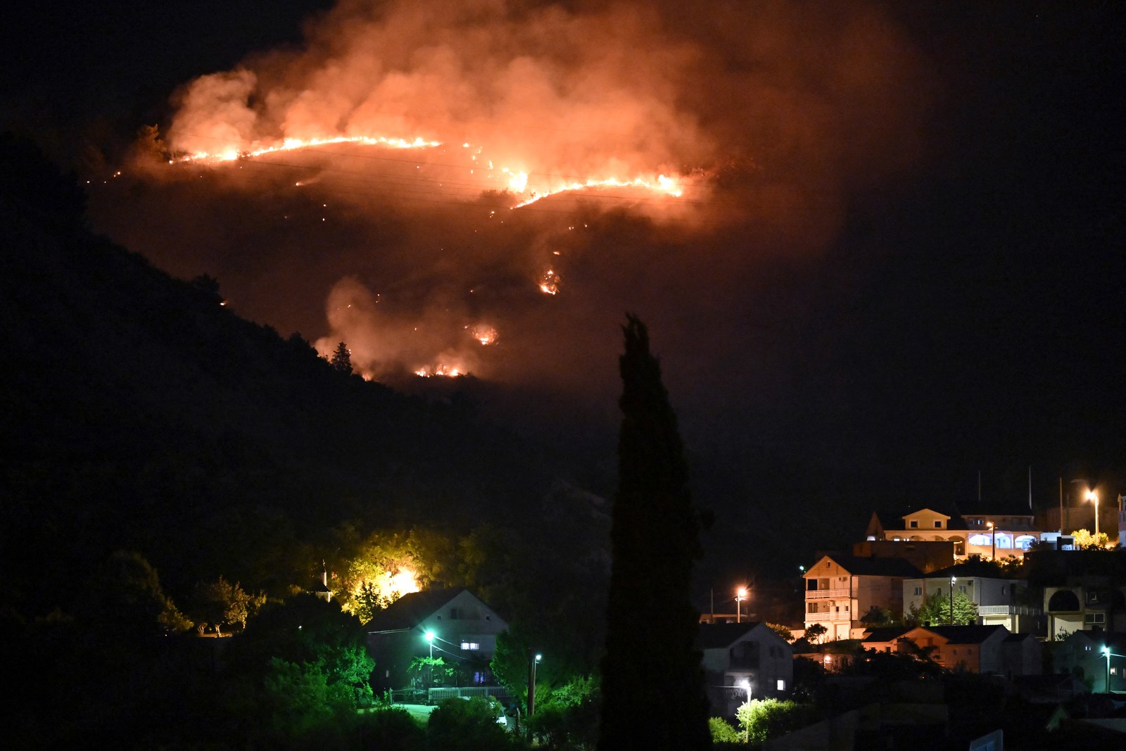 A night view of a wildfire on a hillside.