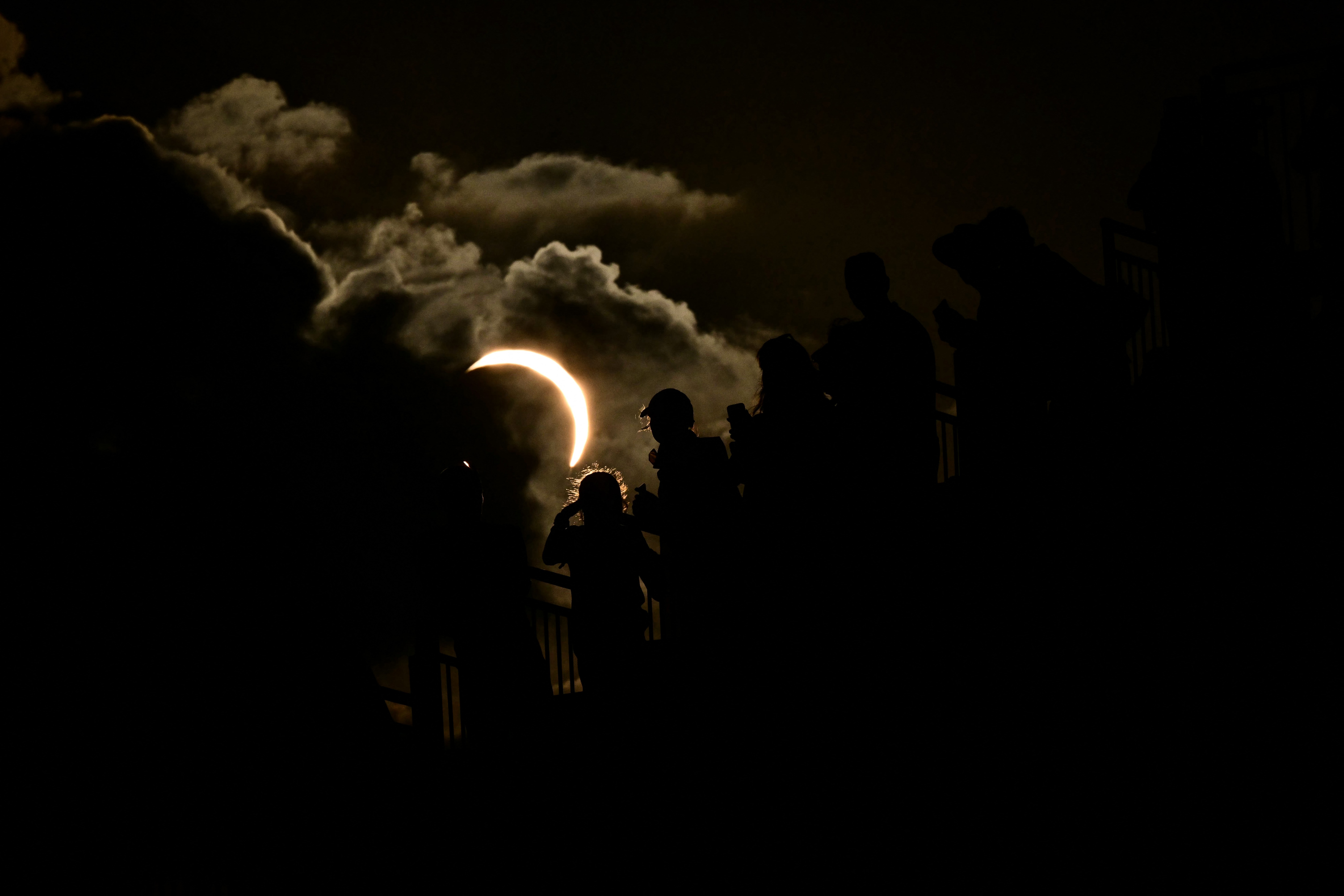 A partial eclipse, seen beyond spectators in a stadium