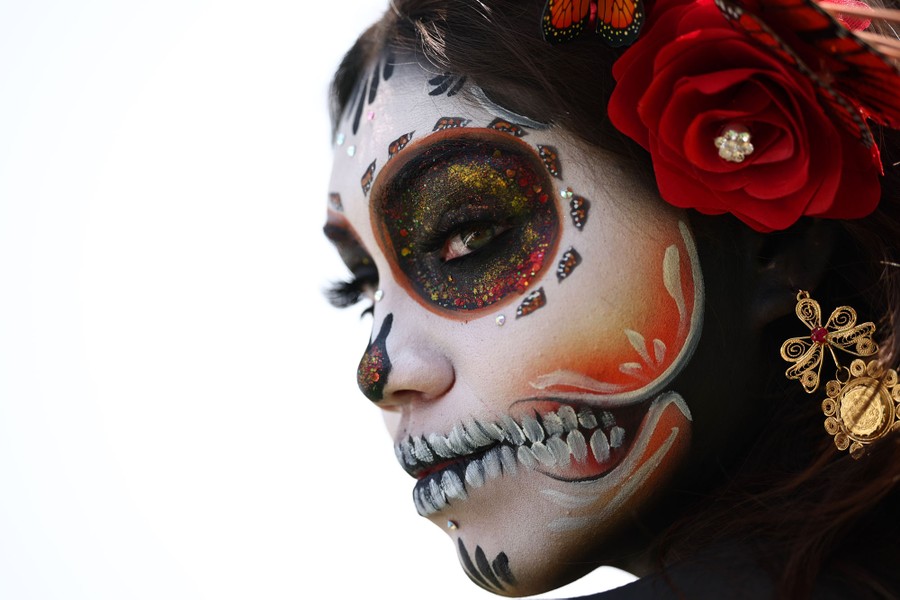 A performer wears ornamental skull makeup on their face.