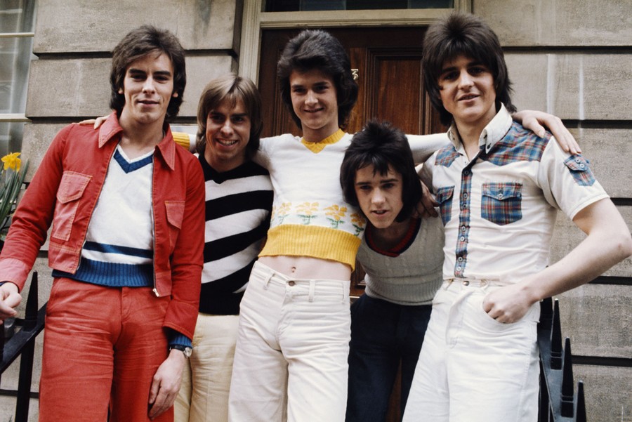 A group photo of five young men standing outside a building
