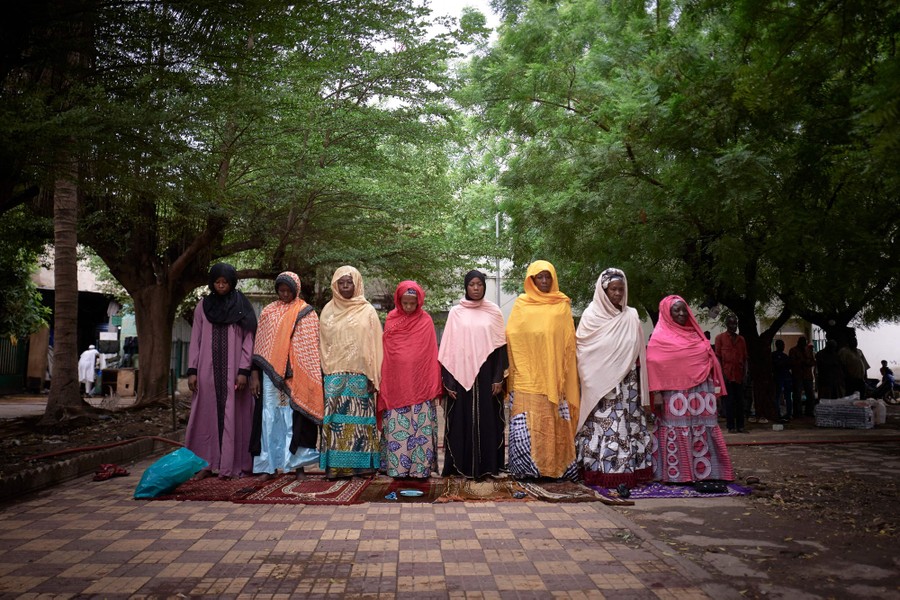 Women gather together to pray in a courtyard.