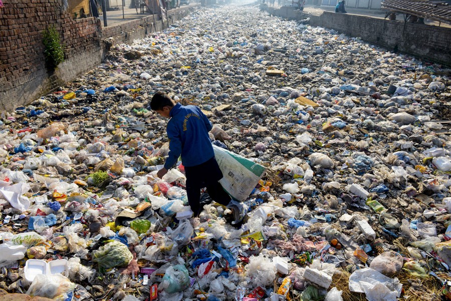 A person picks through garbage in a large dump.