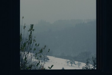 a window in the dark looks out onto a snowy landscape