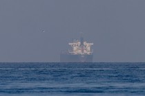 Color photograph of a big ship appearing to materialize through a fog in the Strait of Hormuz.
