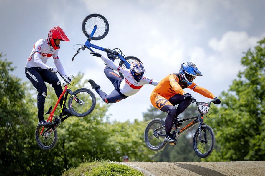 Three BMX riders in the air during a race—the one in the center is falling from his bike.