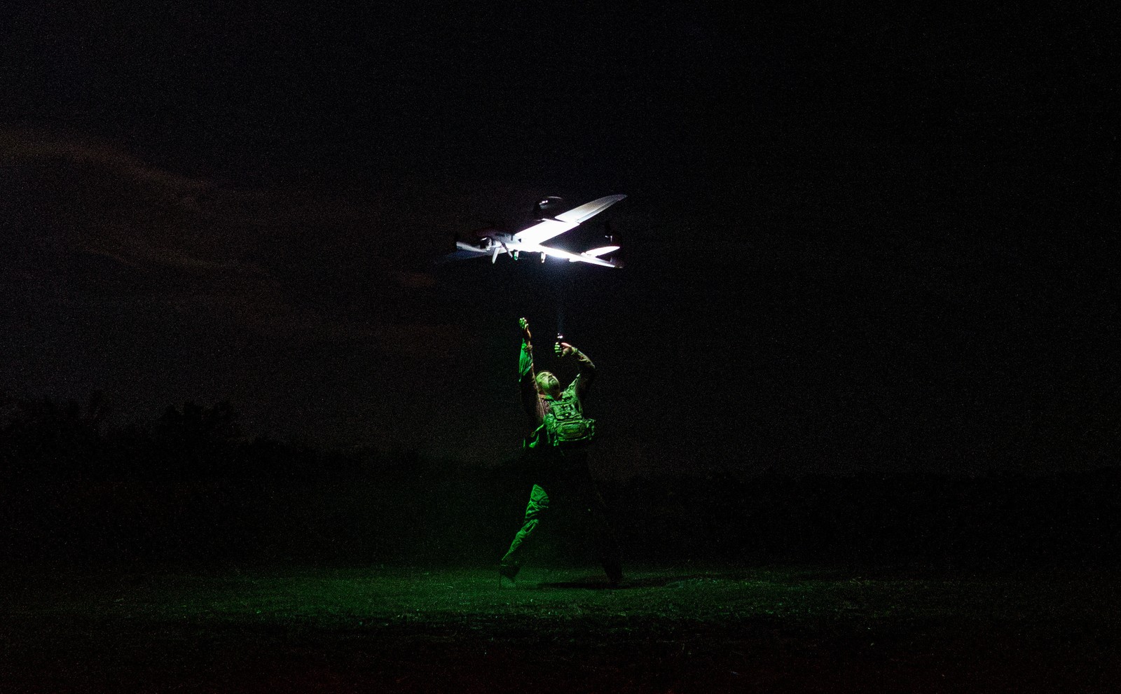 A Ukrainian serviceman launches a fixed-wing reconnaissance drone at night.