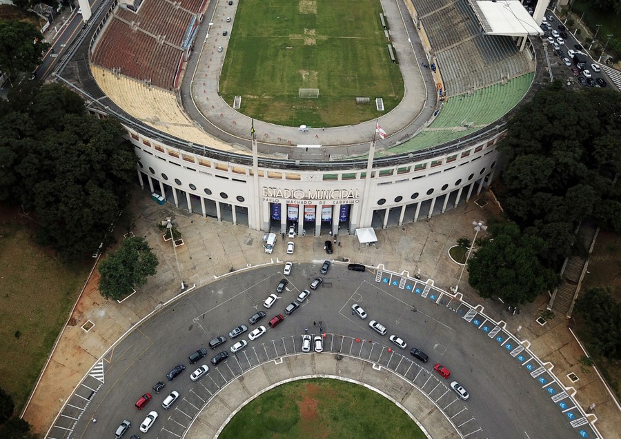 An aerial view of cars driving into a large stadium.