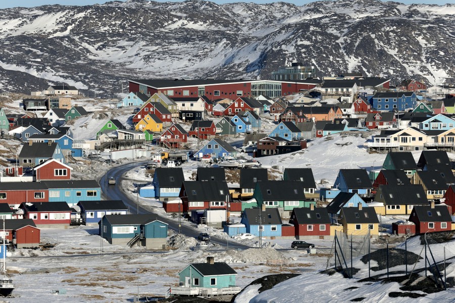 Colorful houses and small buildings sit among snow-covered hills.