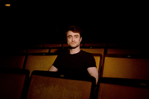 A photograph of actor Daniel Radcliffe Sitting in a theater seat.