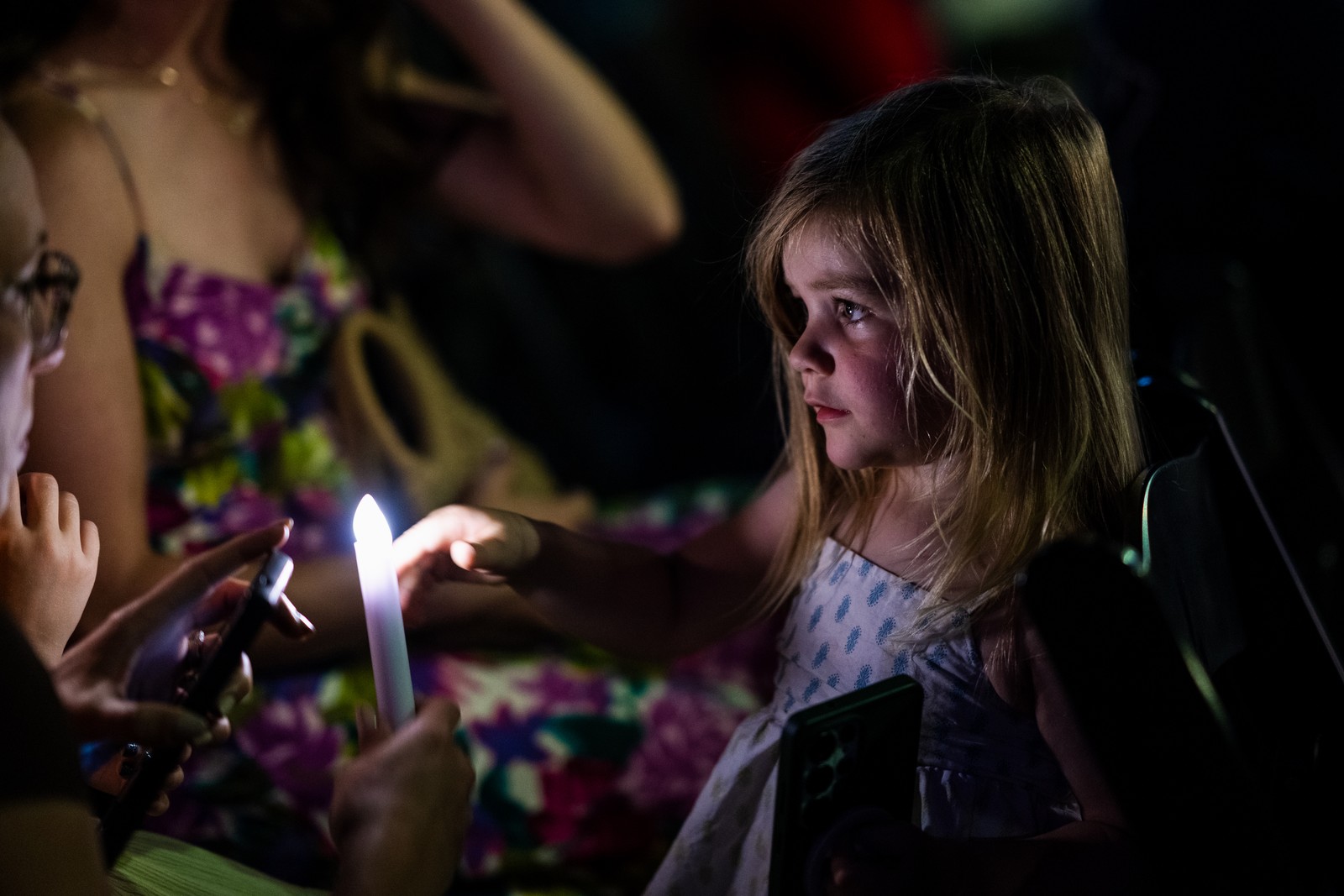 A young girl reaches for a memorial candle.