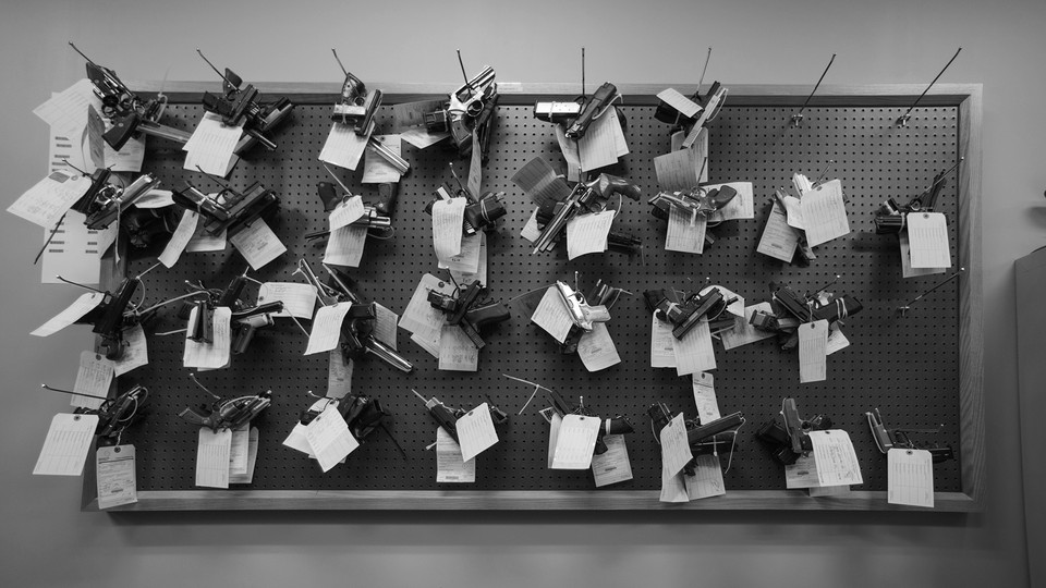 Rows of handguns hanging on a peg board