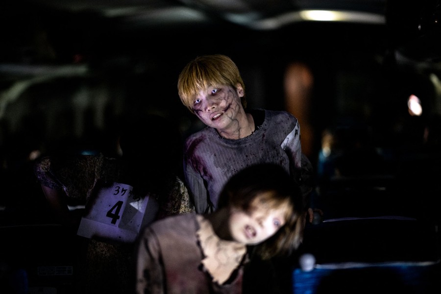 Actors made up like zombies perform for passengers on a train.