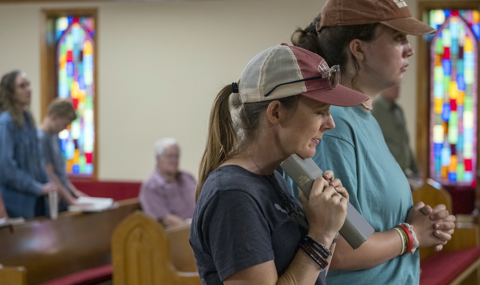 Several people stand and pray inside a church.