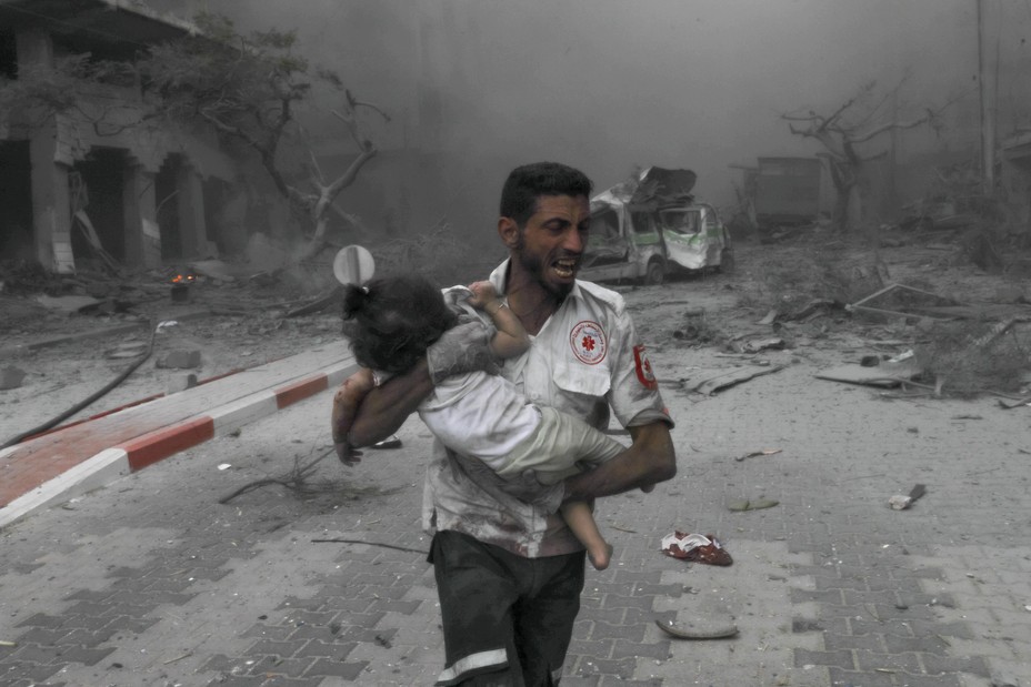 Picture of a medical worker rushing a child to the ambulance for treatment after Israeli airstrikes destroy buildings in Gaza City, Gaza on October 09, 2023.