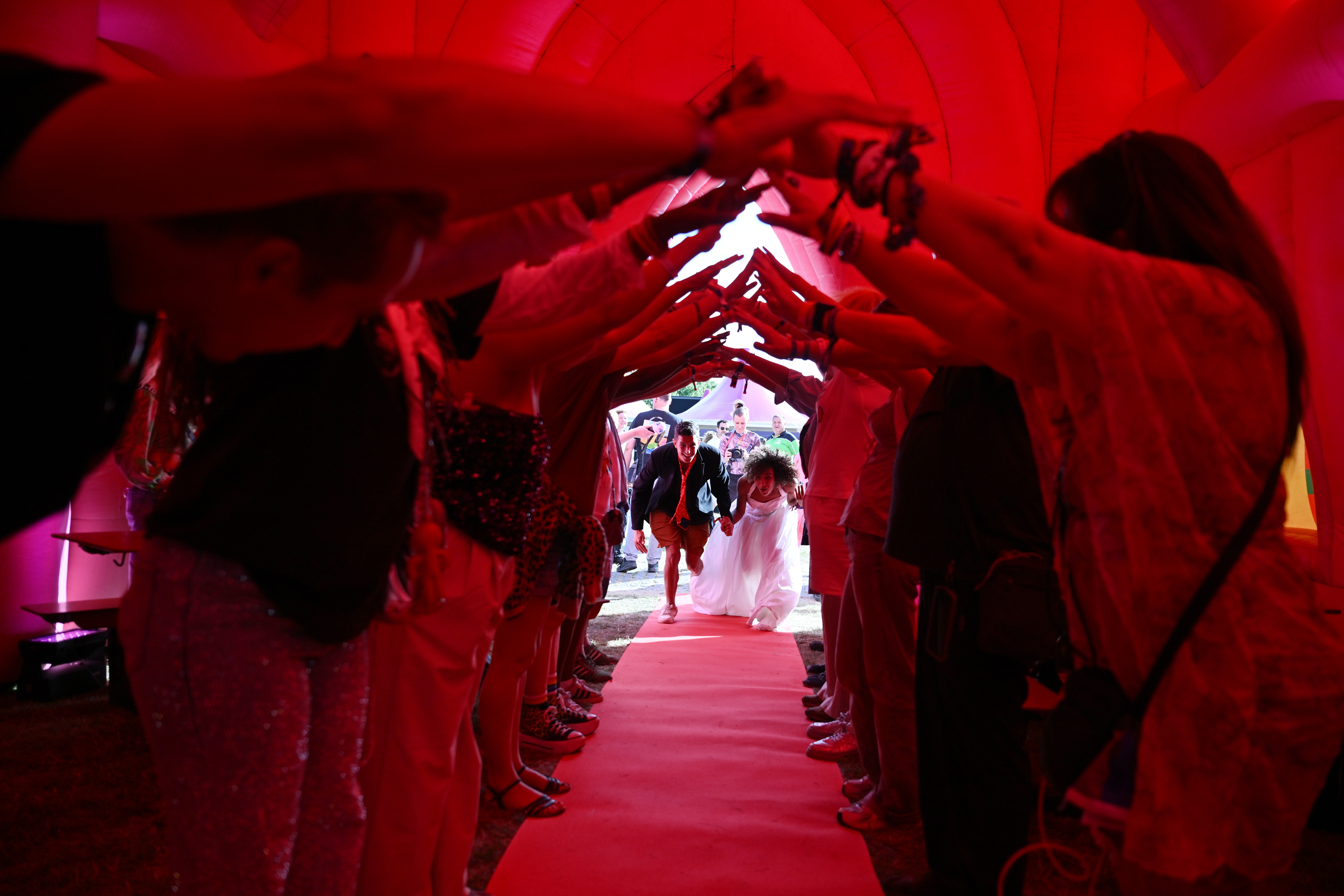 Guests create a human arch for a couple as they enter an inflatable chapel.