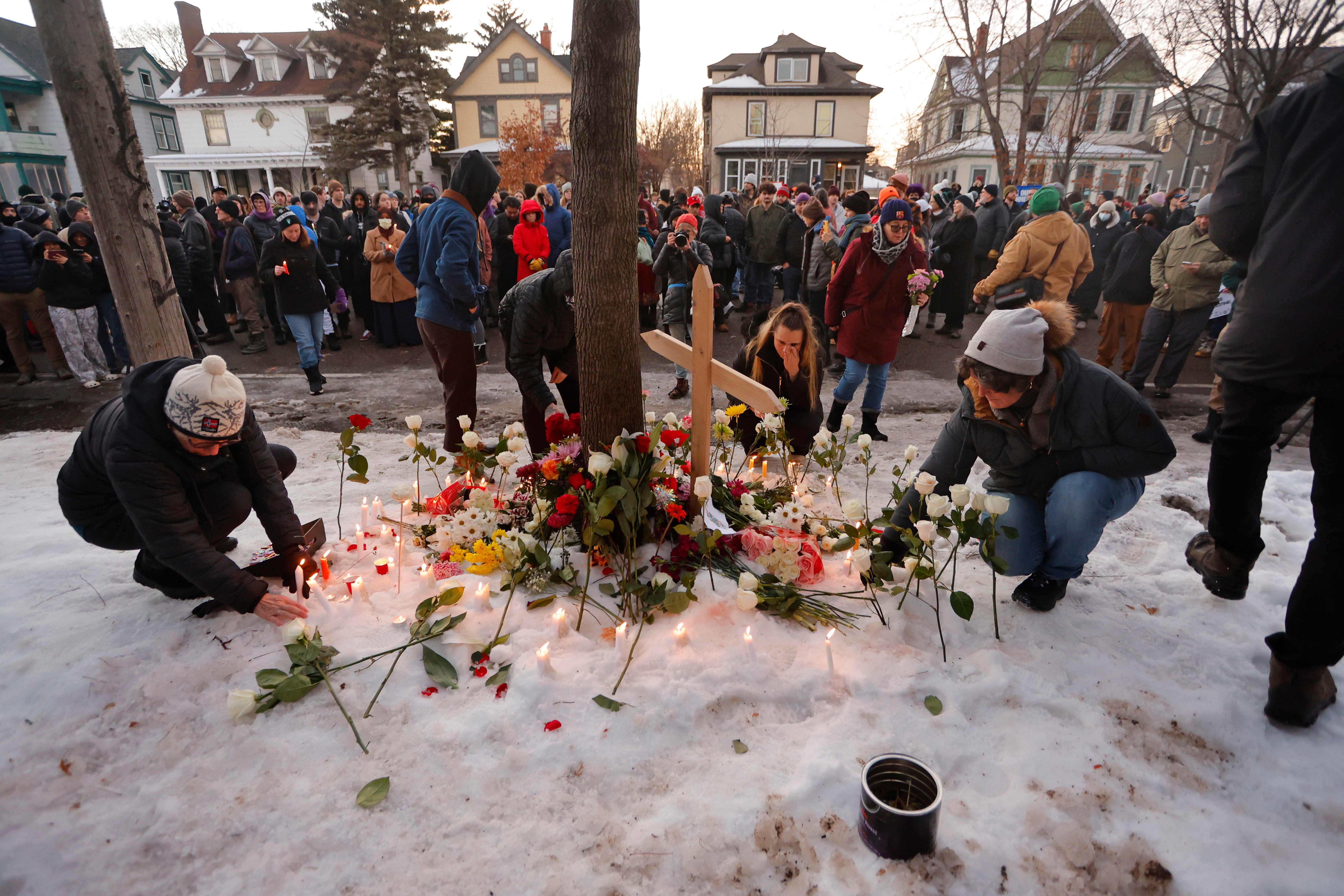People gather for a roadside vigil in a residential neighborhood.