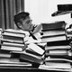 a black and white photo of William F. Buckley sitting at a desk surrounded by books