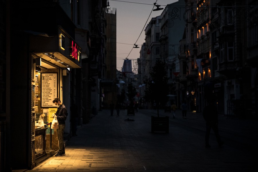 A man stands under lights of a storefront at night.