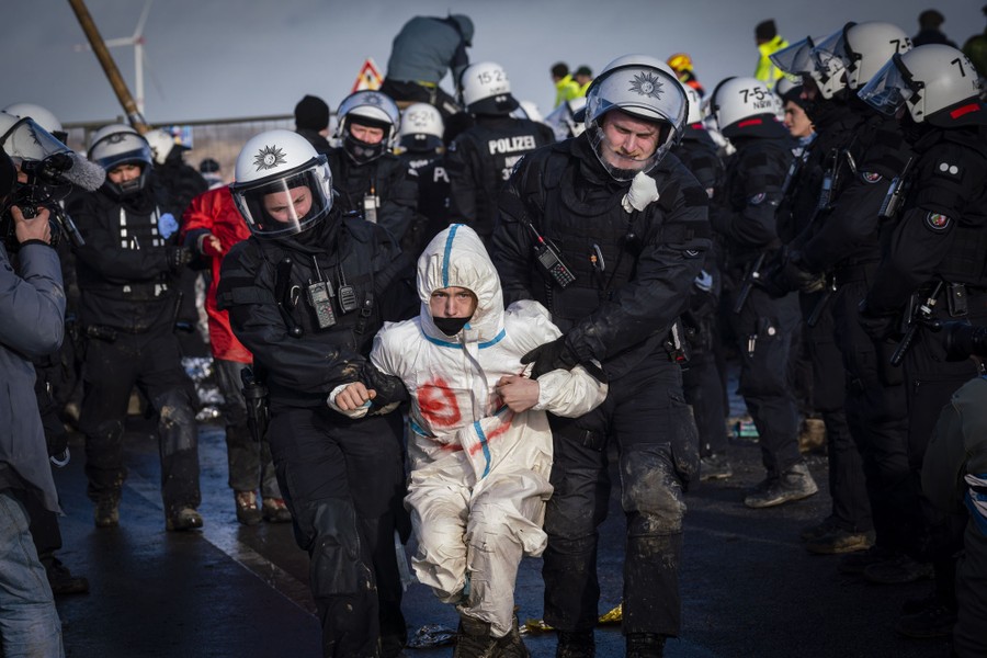 Riot police carry a protester by the arms.