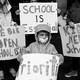 A child holds a sign amid a crowd of other protesters against school closures.
