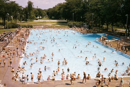 An image of a pool with a lot of people swimming and milling around