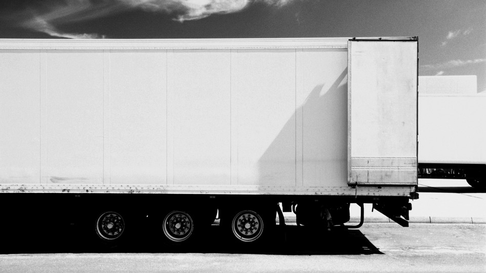 The trailer part of an 18-wheeler, painted white, dominates the frame