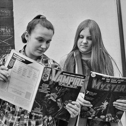 Two teenage girls reading comic books