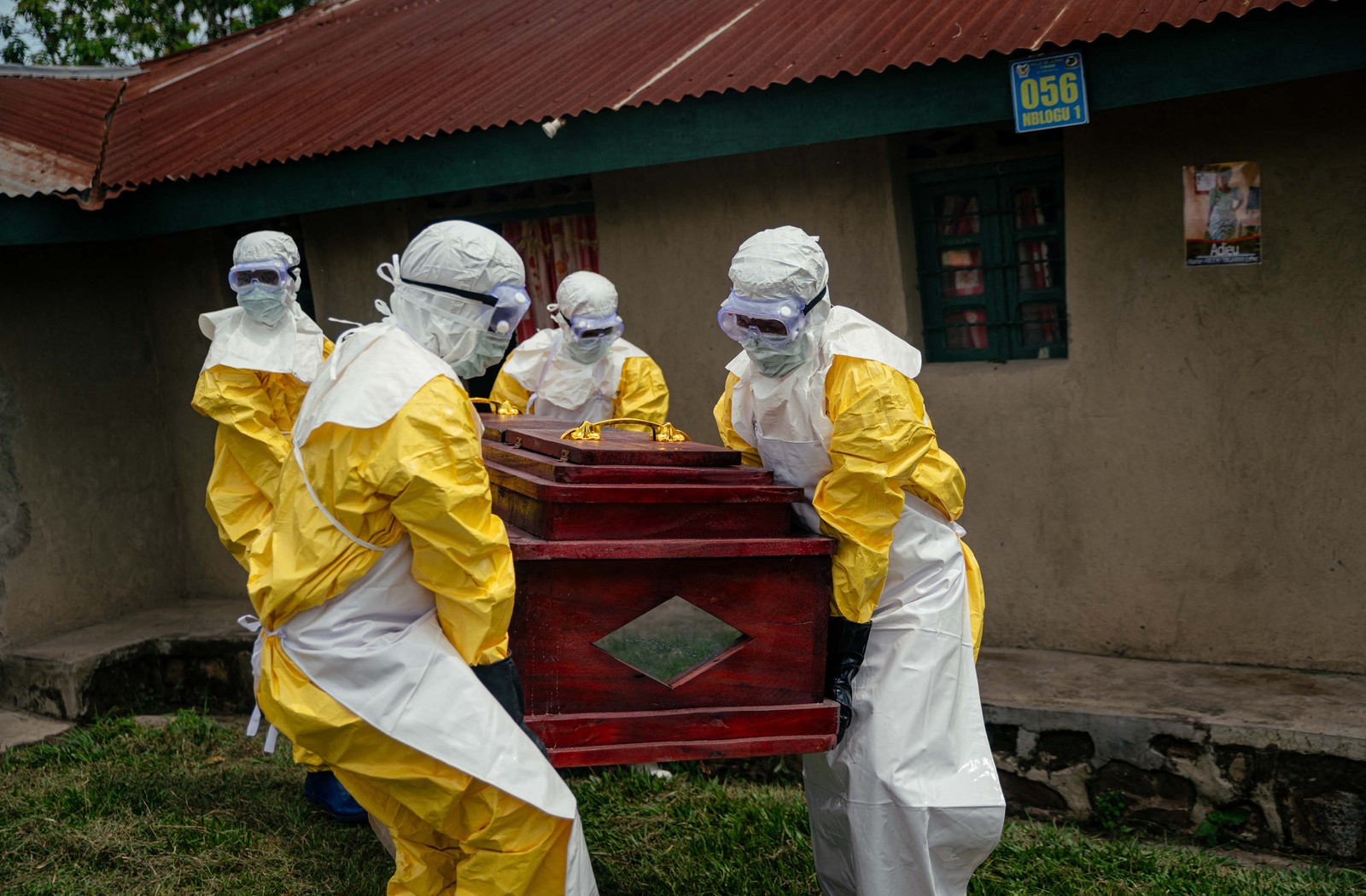 Members of a Congolese Red Cross team wearing personal protective equipment carry the coffin of a woman suspected of having died from Ebola.