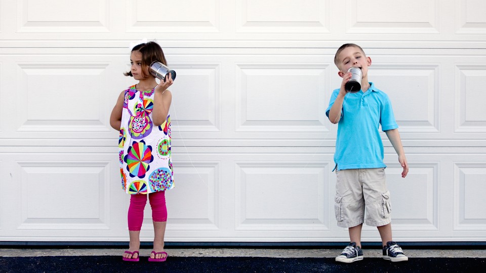 Two children talk with tin-can telephones.