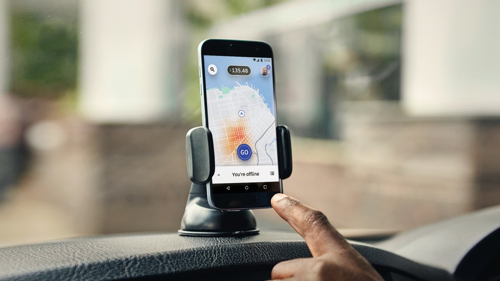 A hand pointing to a smartphone with Uber's app open