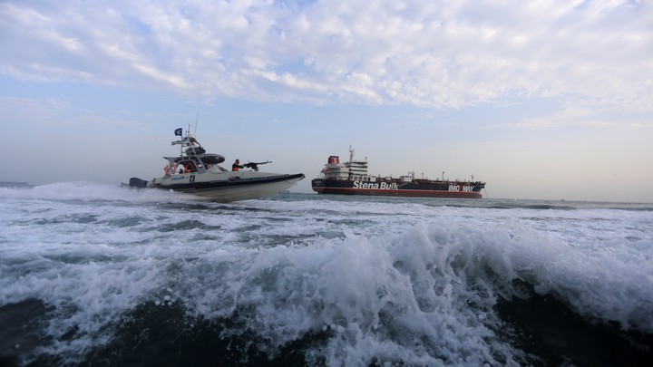 A military speedboat sails close to a tanker.