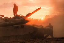 A man standing on top of a tank as the sun sets