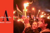 A crowd celebrates Hungarian-election results, waving flags and holding candles.